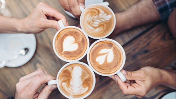 Arial view of 4 hands holding coffee cups