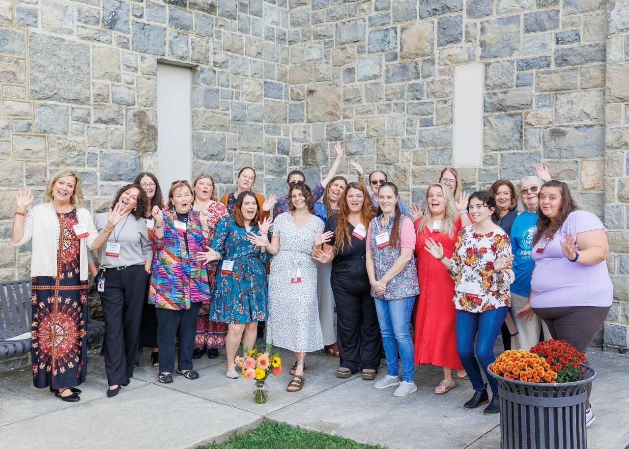 The nominees for the Early Childhood Champion Awards gather in front of a Hokie Stone wall and cheer.